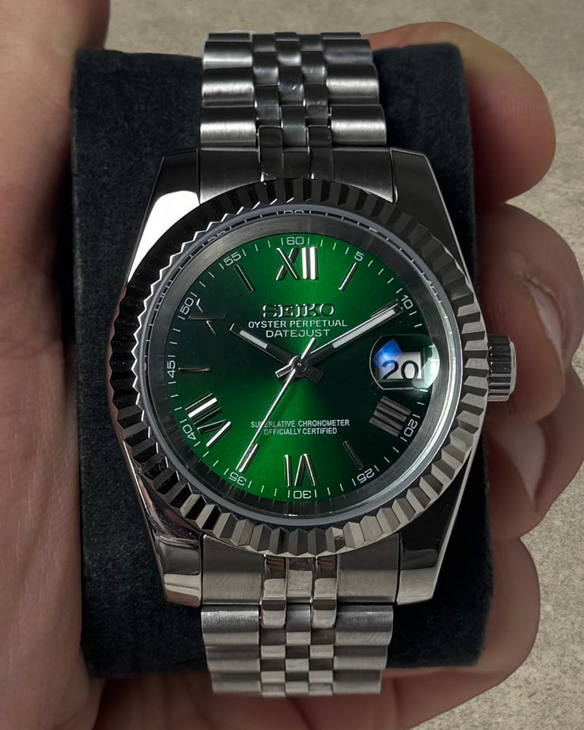 PB TimePiece Classic Date watch with emerald green dial, Roman numerals, fluted bezel, and stainless steel bracelet.