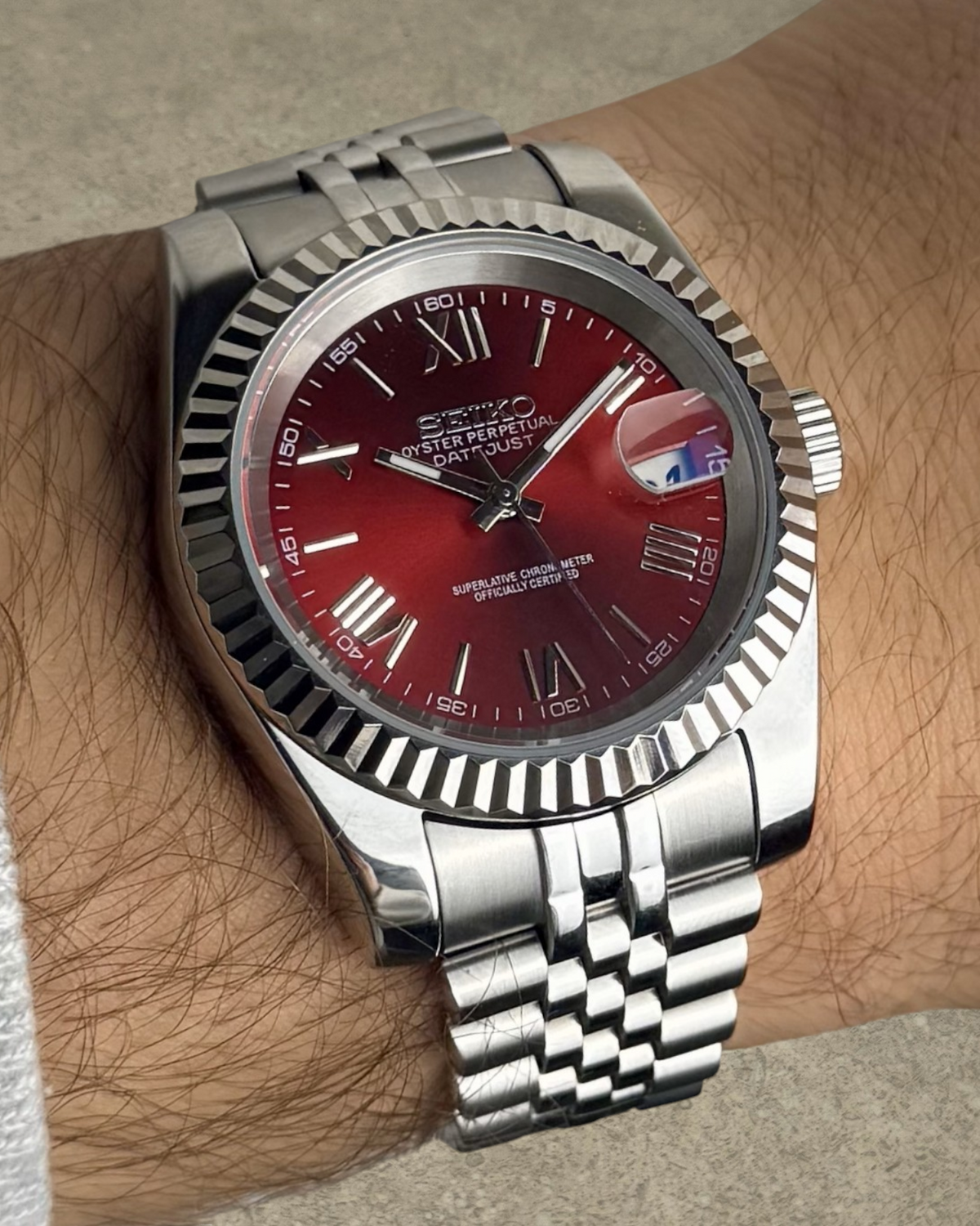 PB TimePiece Classic Date watch with a cherry red dial, Roman numerals, fluted bezel, and stainless steel bracelet.