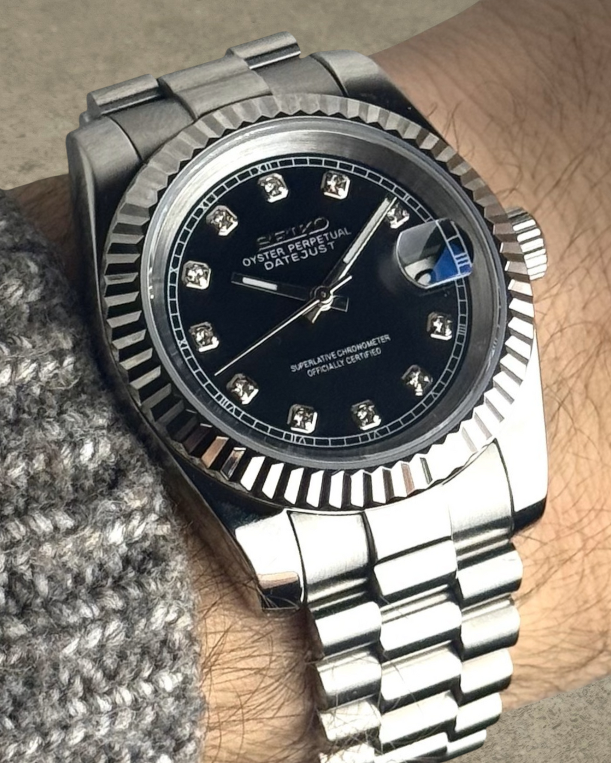 PB TimePiece Classic Date watch with a jet black dial, crystal markers, fluted bezel, and stainless steel bracelet.