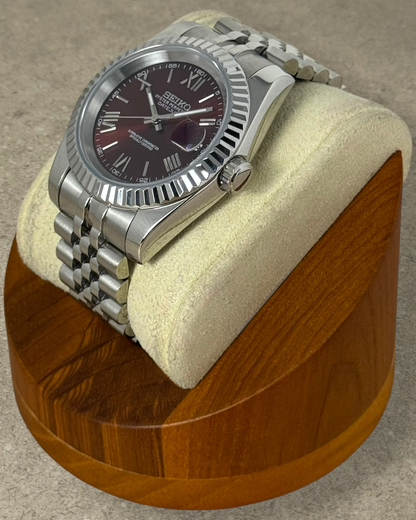 PB TimePiece Classic Date watch with a burgundy dial, Roman numerals, fluted bezel, and stainless steel jubilee band.