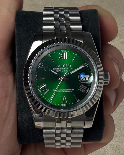 PB TimePiece Classic Date watch with emerald green dial, Roman numerals, fluted bezel, and stainless steel bracelet.