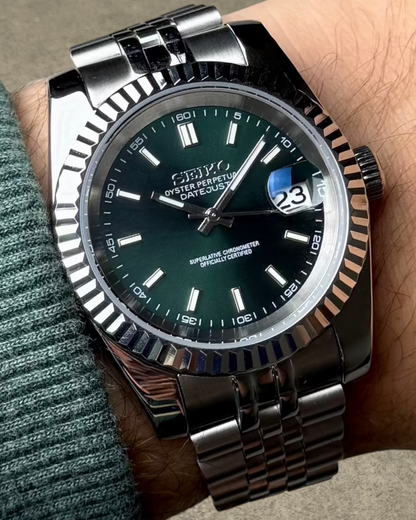PB TimePiece Classic Date watch with a forest green dial, fluted bezel, and stainless steel jubilee bracelet on wrist
