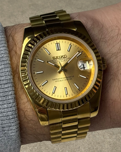 PB TimePiece Classic Date gold stainless steel watch with champagne dial, fluted bezel, and presidential bracelet.