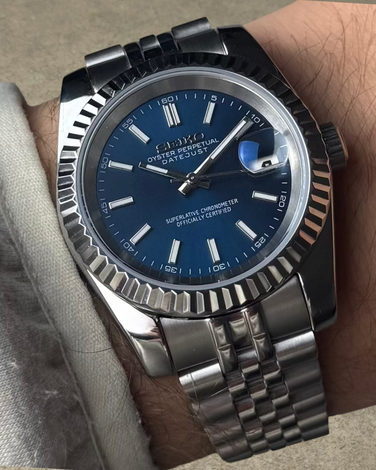 PB TimePiece Classic Date watch with a navy blue dial, stainless steel jubilee bracelet, and fluted bezel on wrist.