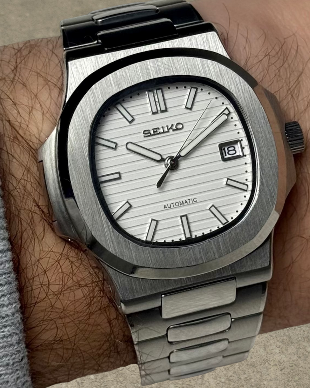 PB TimePiece Novara watch featuring a textured white dial, stainless steel case, and bracelet on a wrist.