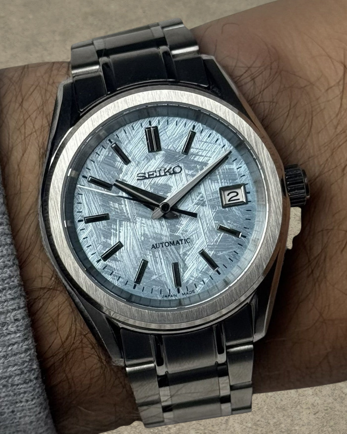 PB TimePiece Heritage watch with an ice blue textured dial, stainless steel case, and bracelet on a wrist.