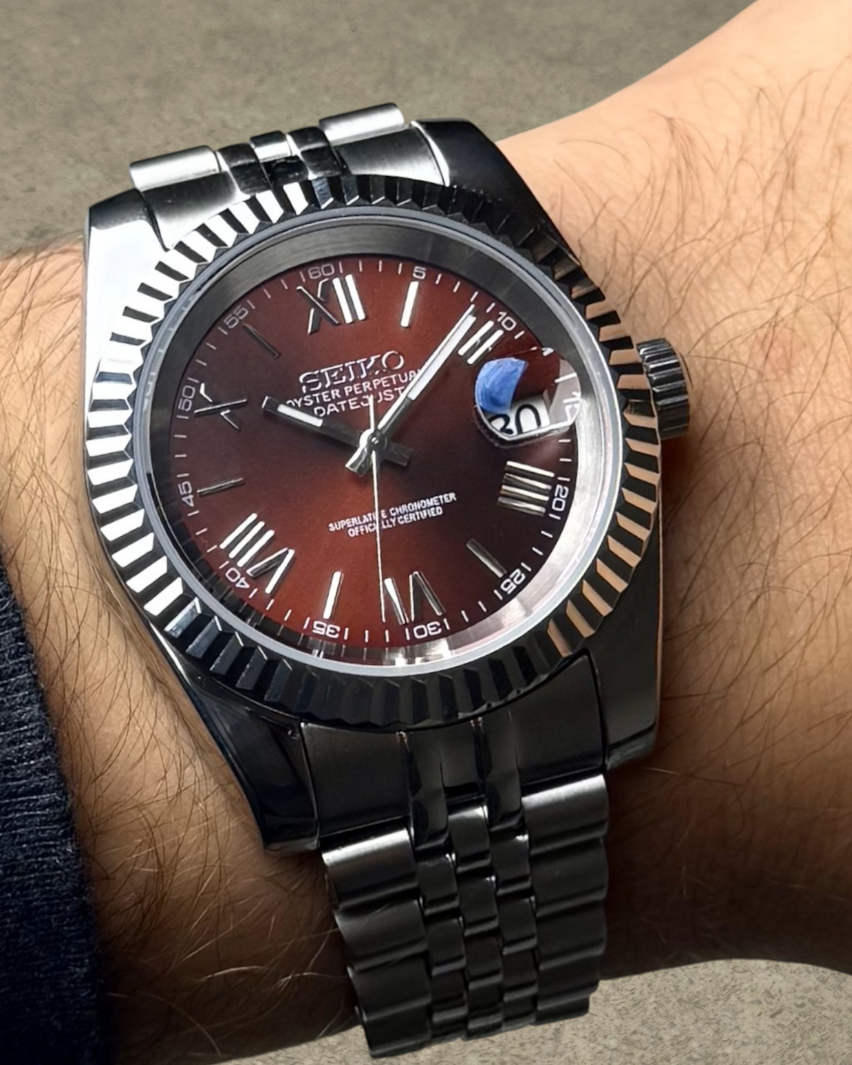 PB TimePiece Classic Date watch with burgundy dial, Roman numerals, fluted bezel, and stainless steel jubilee bracelet