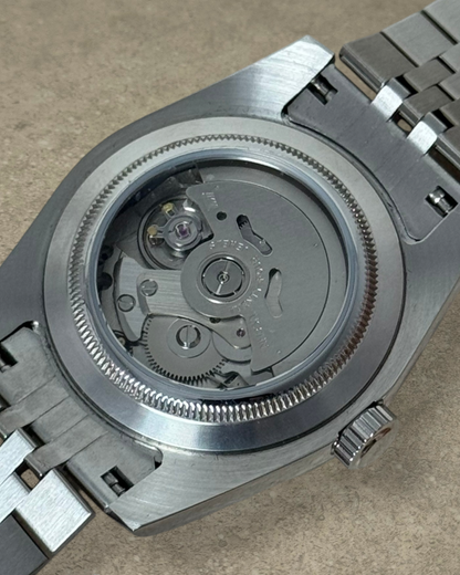 PB TimePiece Classic Date watch showing the exhibition case back with automatic Seiko NH35 movement and jubilee band