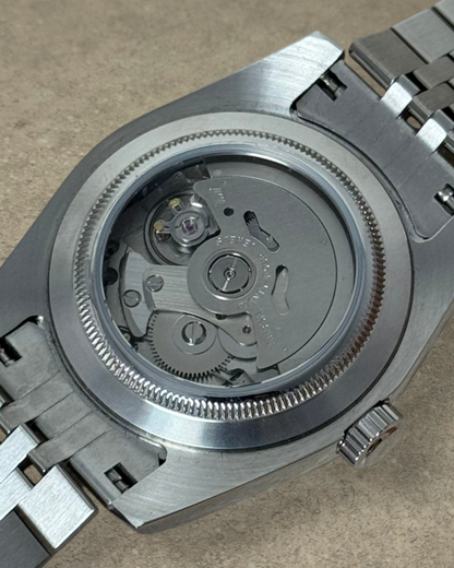 PB TimePiece Classic Date watch showing the exhibition case back with automatic Seiko NH35 movement and steel bracelet
