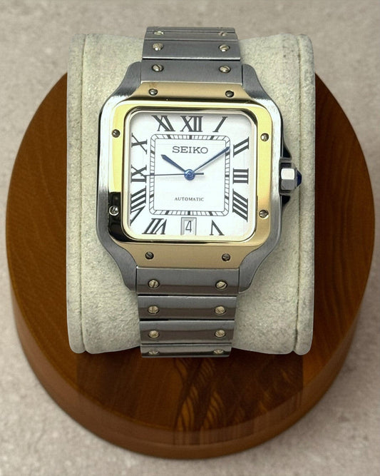 PB TimePiece Aviator watch with a two-tone gold and stainless steel case, white dial, Roman numerals, and blue hands.