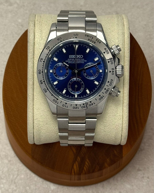 PB TimePiece chronograph watch with a blue dial, stainless steel case, and polished oyster bracelet on a display.