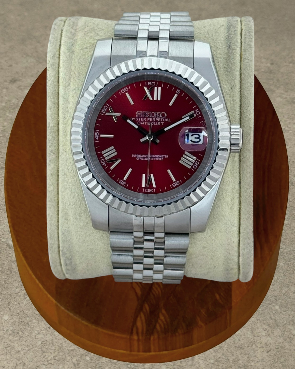PB TimePiece Classic Date watch with a cherry red dial, Roman numerals, fluted bezel, and stainless steel bracelet.