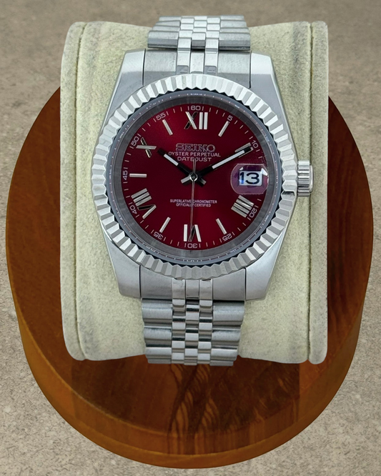 PB TimePiece Classic Date watch with a cherry red dial, Roman numerals, fluted bezel, and stainless steel bracelet.