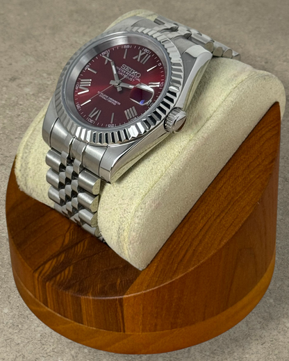 PB TimePiece Classic Date watch with cherry red dial, Roman numerals, fluted bezel, and stainless steel jubilee band.