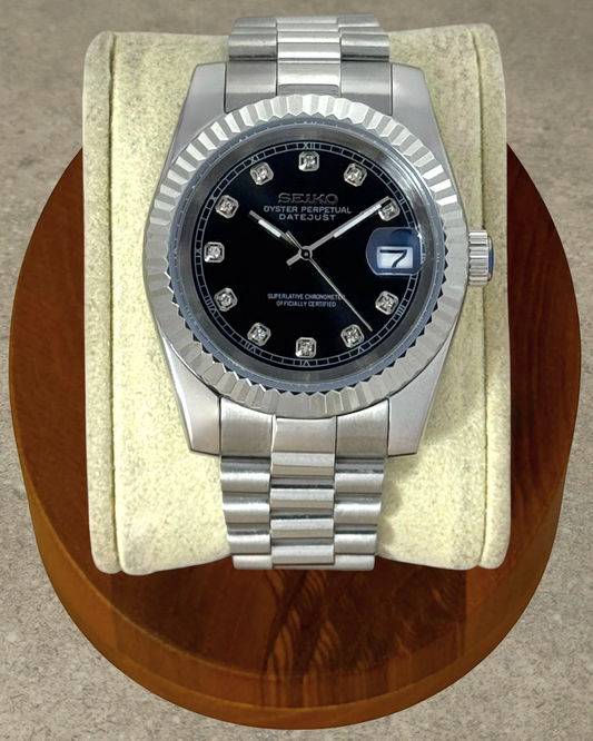 PB TimePiece Classic Date watch with a jet black dial, crystal markers, fluted bezel, and stainless steel bracelet.