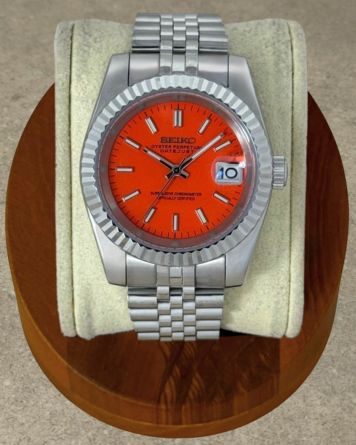 PB TimePiece Classic Date watch with a vibrant orange dial, stainless steel jubilee bracelet, and fluted bezel.