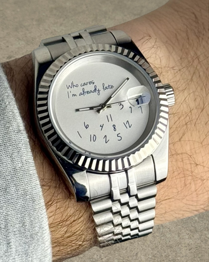 PB TimePiece Classic Date watch with stainless steel jubilee bracelet, fluted bezel, and whimsical dial text.