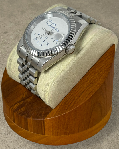 PB TimePiece Classic Date watch with white dial, fluted bezel, and stainless steel jubilee bracelet on wood stand