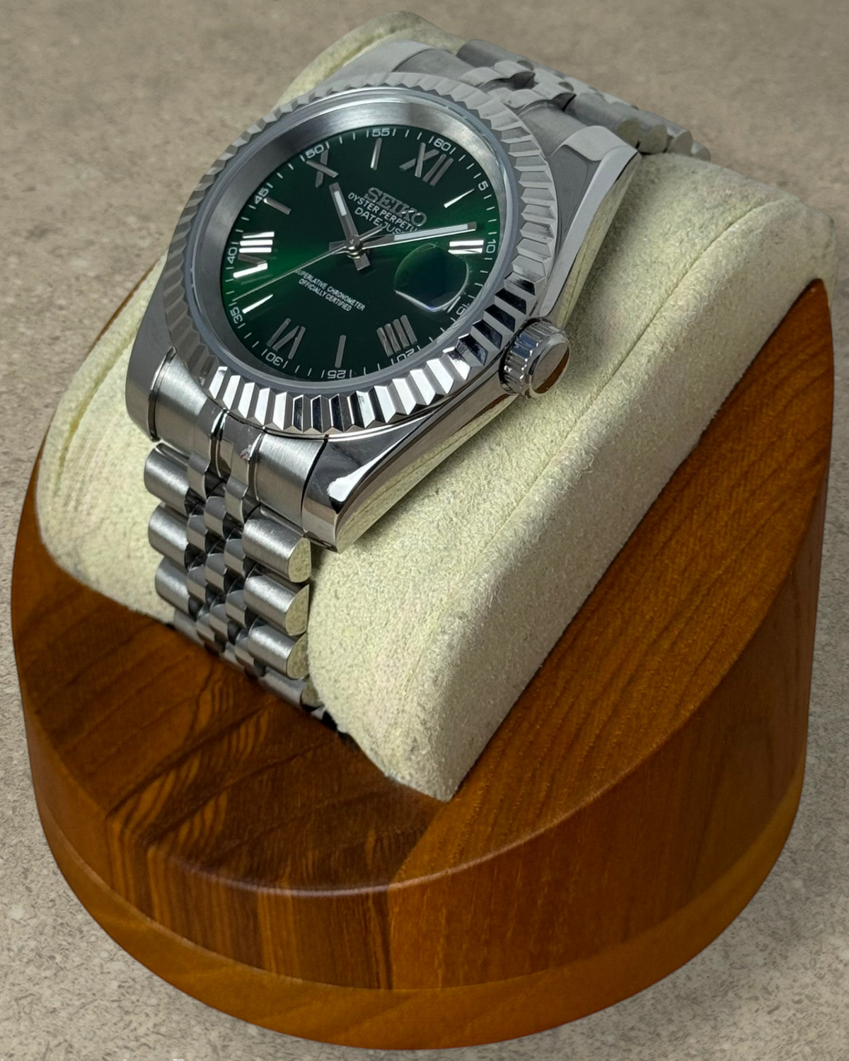 PB TimePiece Classic Date watch with emerald green dial, Roman numerals, fluted bezel, and stainless steel bracelet.