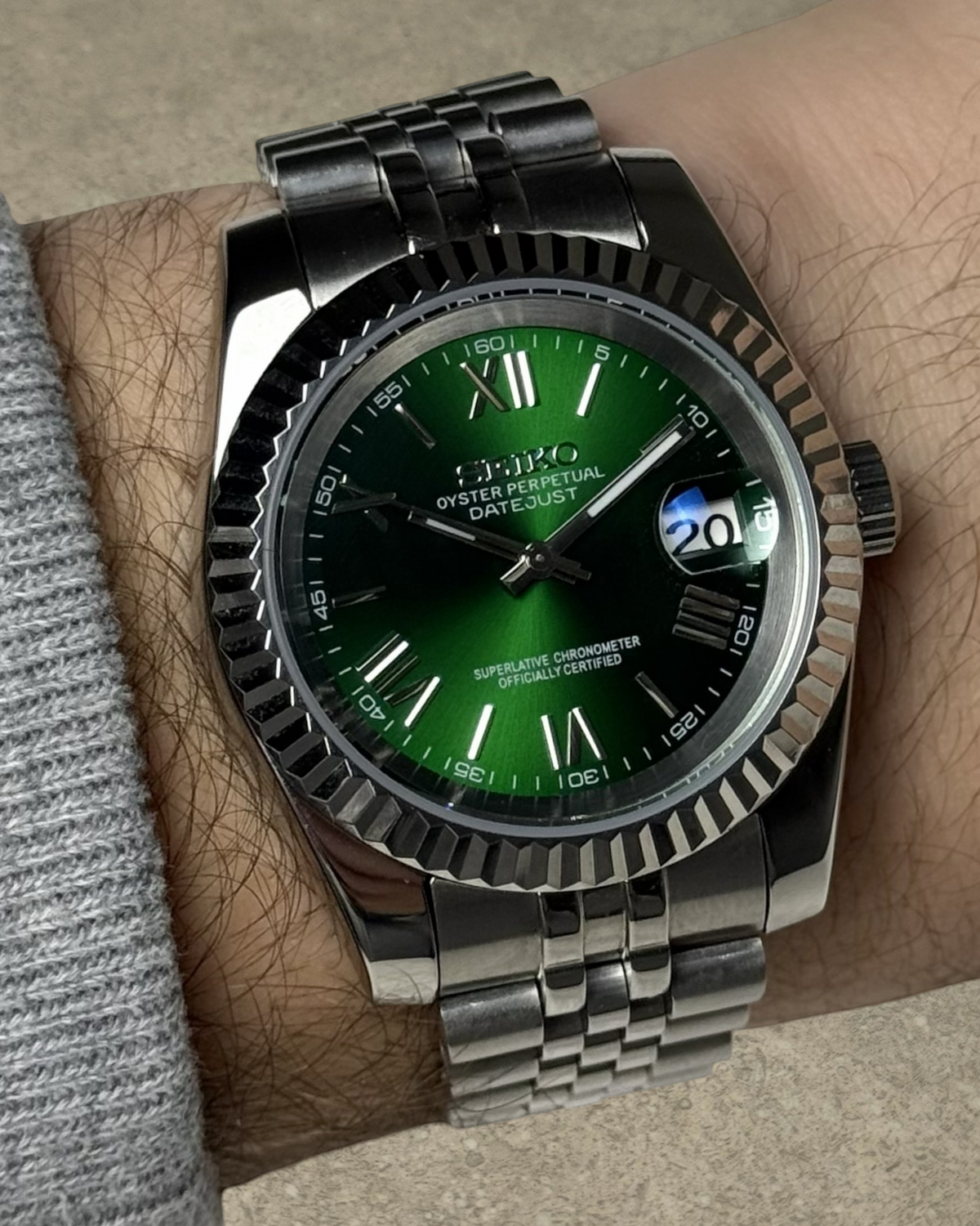 PB TimePiece Classic Date watch with emerald green dial, Roman numerals, fluted bezel, and stainless steel bracelet.