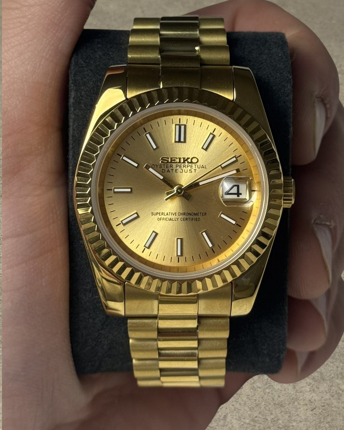 PB TimePiece Classic Date gold stainless steel watch with champagne dial, fluted bezel, and presidential bracelet.