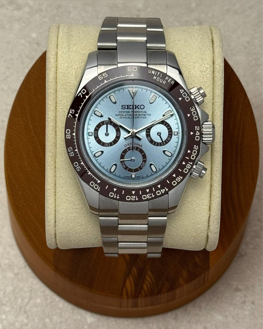 PB TimePiece chronograph watch with an ice blue dial, brown bezel, and stainless steel oyster bracelet.