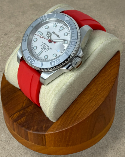 PB TimePiece Marinemaster watch with a white dial, red rubber strap, and matte gray rotating bezel on a display stand
