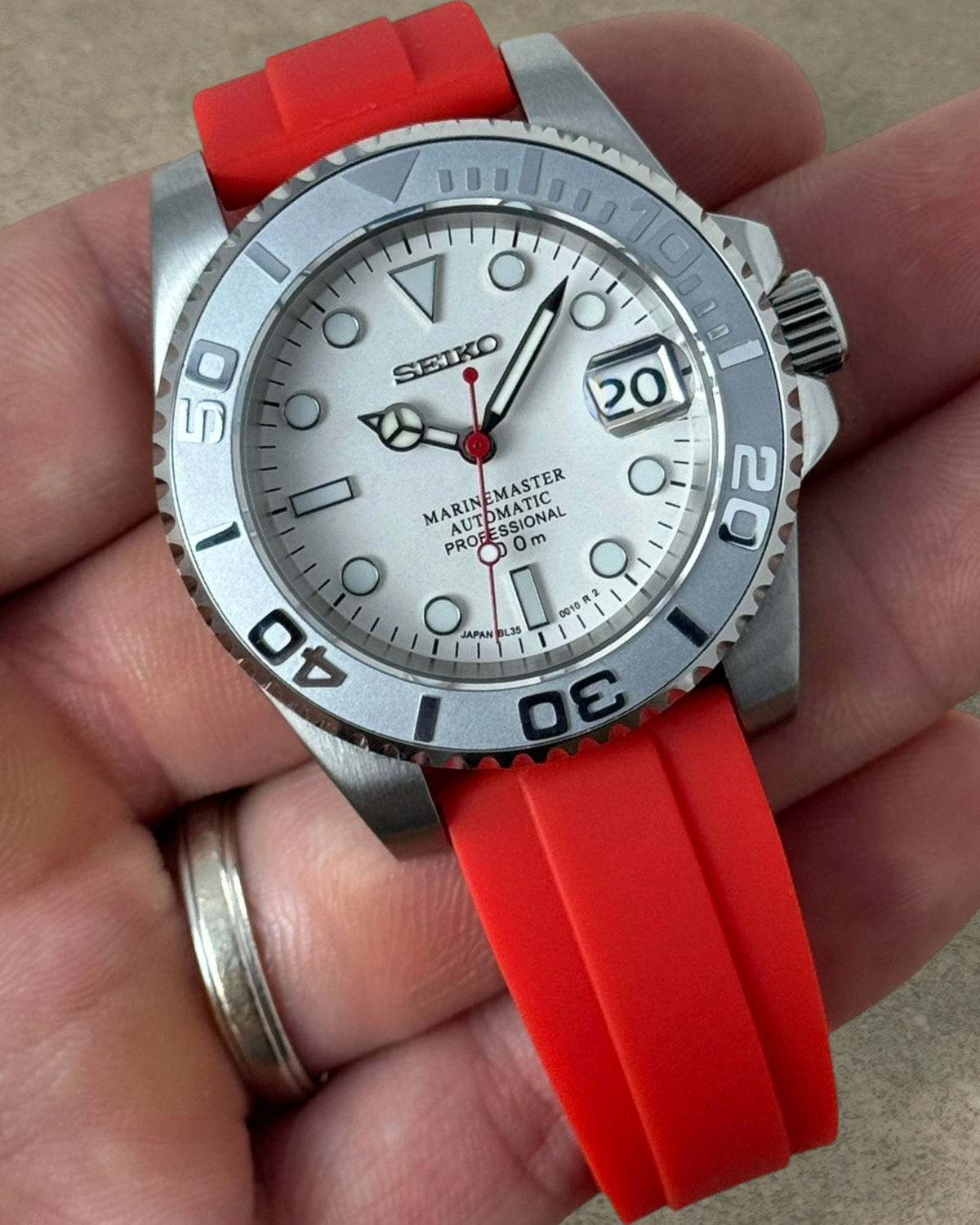 PB TimePiece Marinemaster watch with a white dial, matte gray bezel, and vibrant crimson red rubber strap.