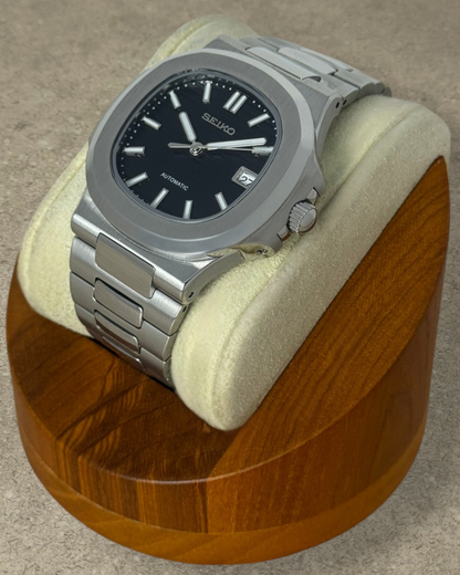 PB TimePiece Novara automatic watch with a textured black dial, stainless steel case, and brushed metal bracelet.