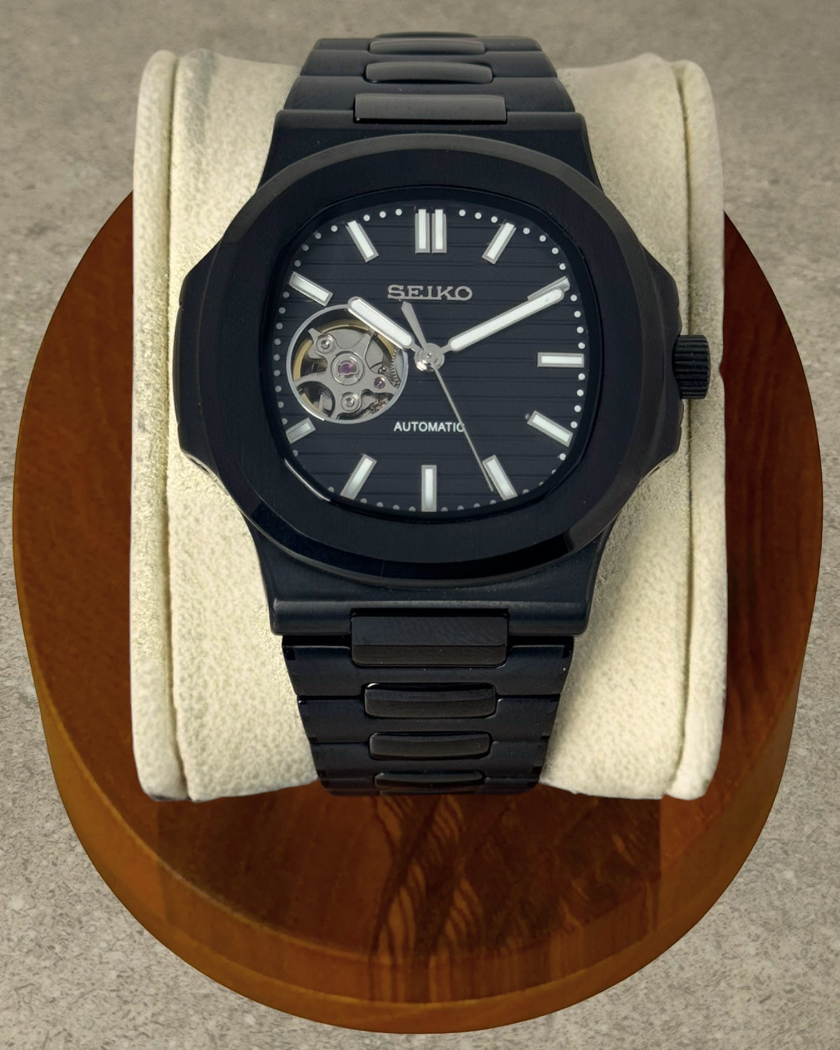 PB TimePiece Novara automatic watch with a black stainless steel case, bracelet, and open heart dial on a display.