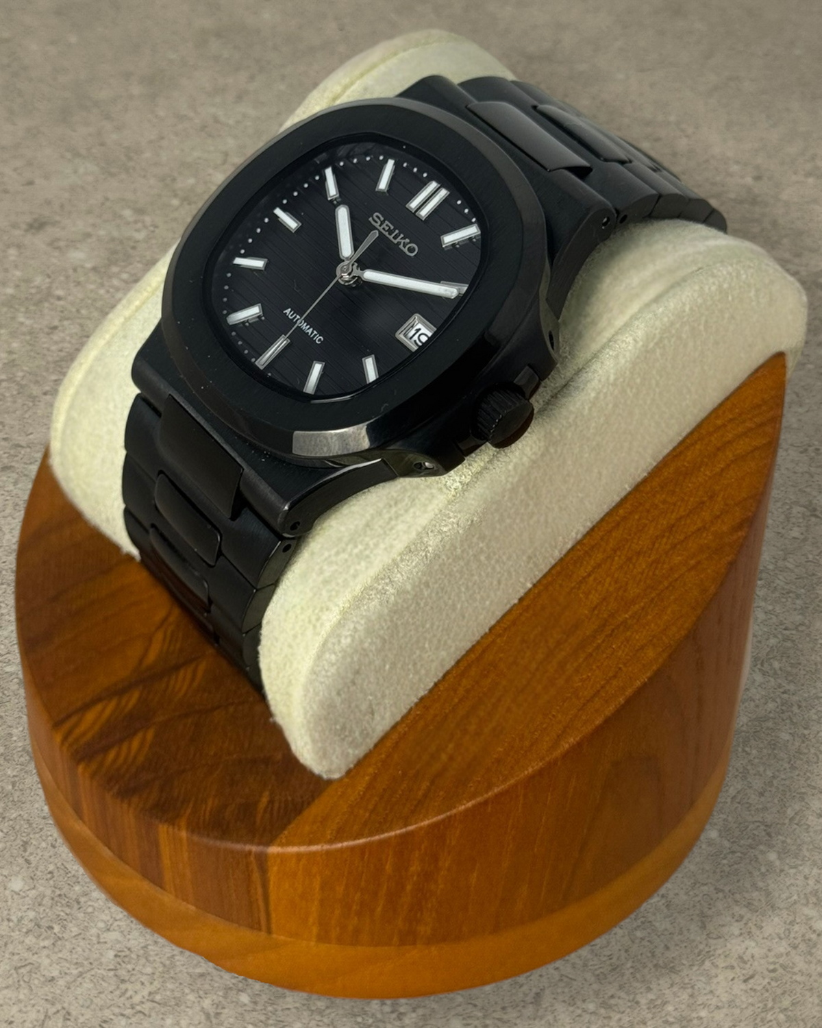 PB TimePiece Novara black stainless steel automatic watch with a textured dial and brushed finish on a display stand.