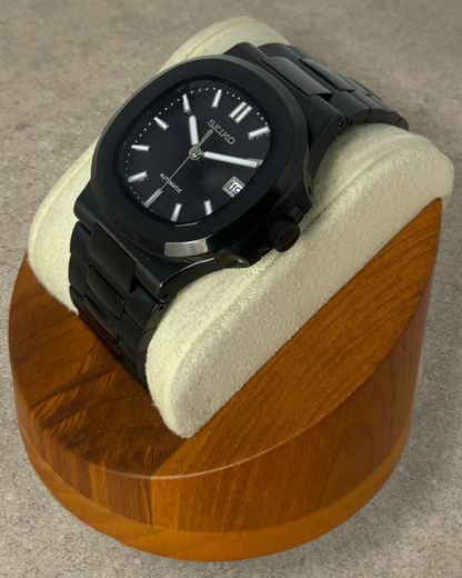 PB TimePiece Novara black stainless steel automatic watch with a textured dial and brushed finish on a display stand.