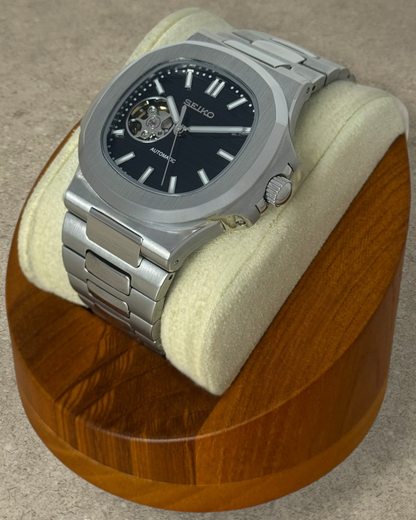 PB TimePiece Novara automatic watch with a black open heart dial, stainless steel case, and brushed link bracelet.