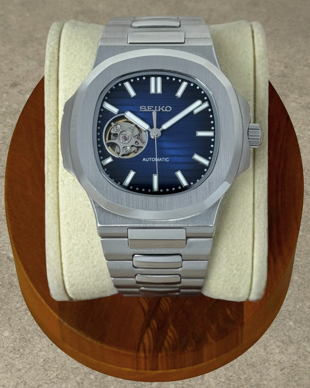 PB TimePiece Novara automatic watch with a blue open heart dial, stainless steel case, and brushed link bracelet.
