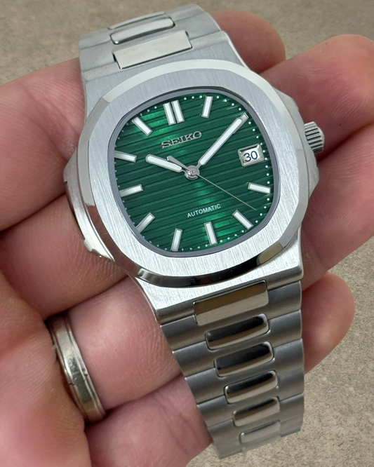PB TimePiece Novara watch with a textured emerald green dial, stainless steel case, and brushed link bracelet.