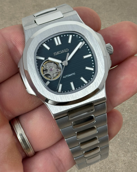 PB TimePiece Novara automatic watch with a forest green open heart dial, stainless steel case, and bracelet.
