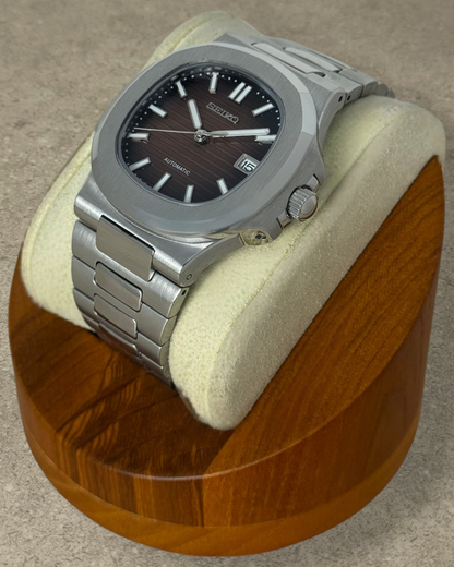 PB TimePiece Novara watch featuring a textured ombre brown dial, stainless steel case, and bracelet on a wooden stand.