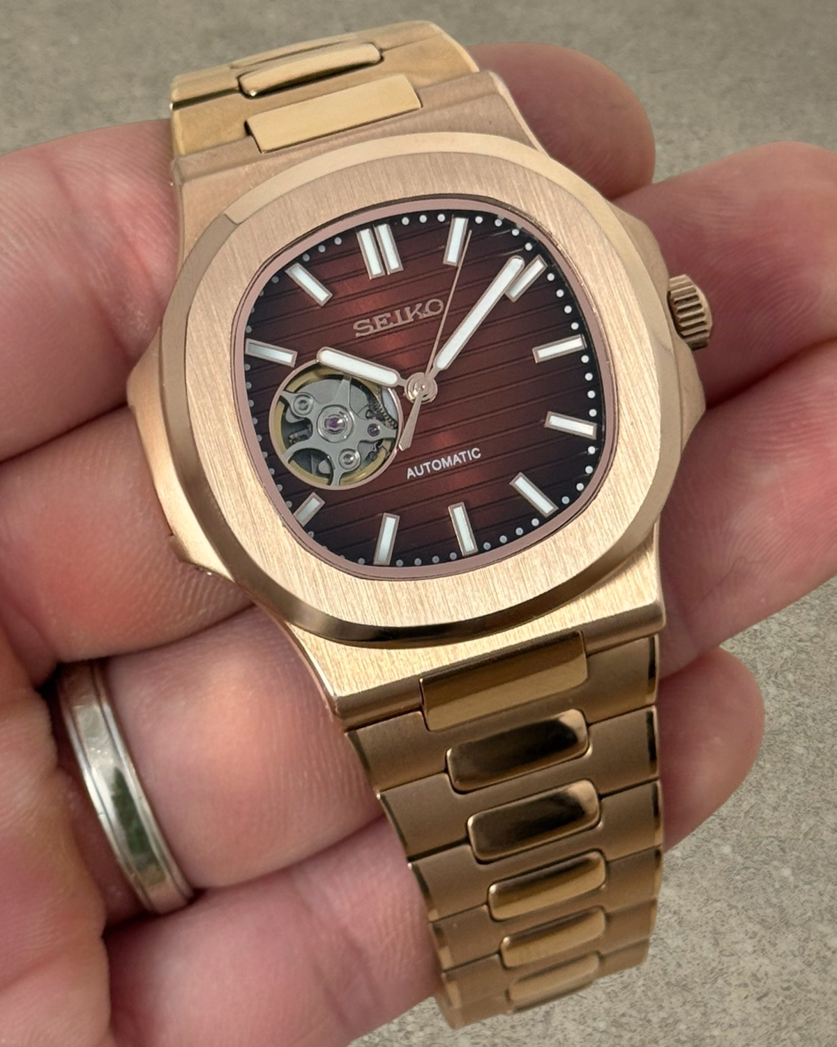 PB TimePiece Novara rose gold automatic watch with an open heart chocolate dial and stainless steel bracelet.