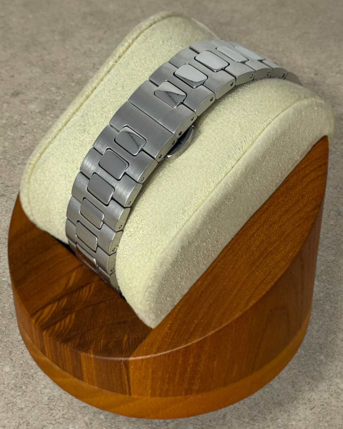 PB TimePiece Novara watch featuring a brushed stainless steel bracelet with a butterfly clasp on a wooden stand.