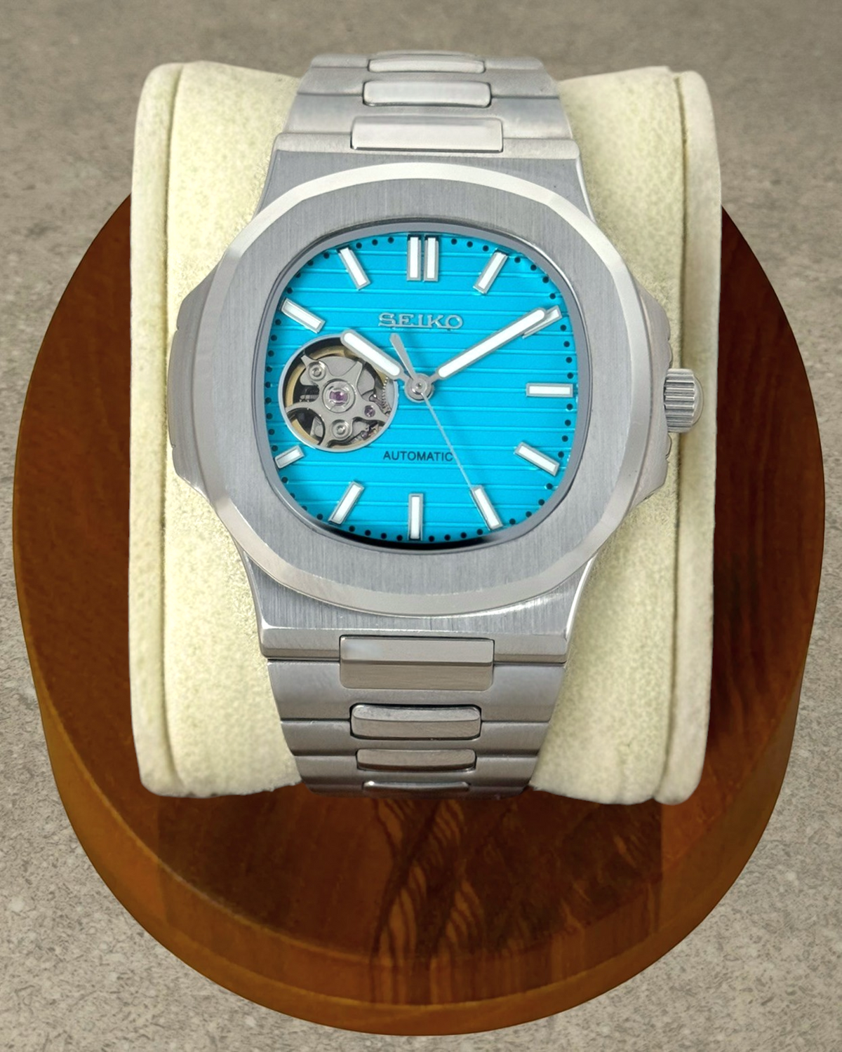 PB TimePiece Novara automatic watch with a teal blue open heart dial, stainless steel case, and brushed bracelet.