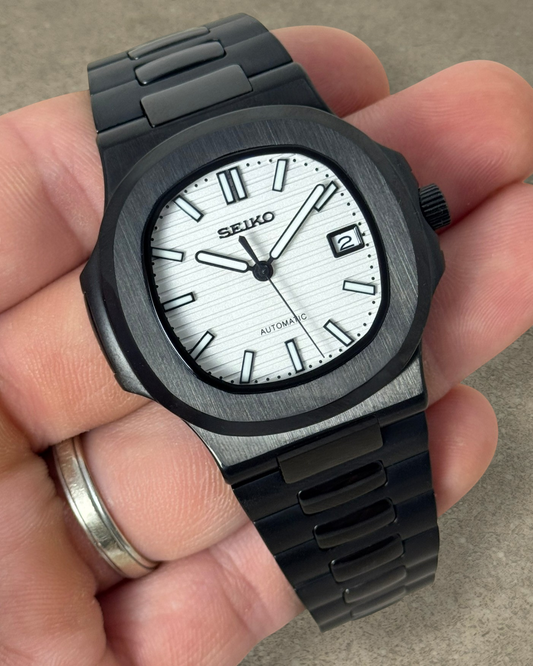 PB TimePiece Novara watch with a textured white dial, black stainless steel case, and matching black bracelet.