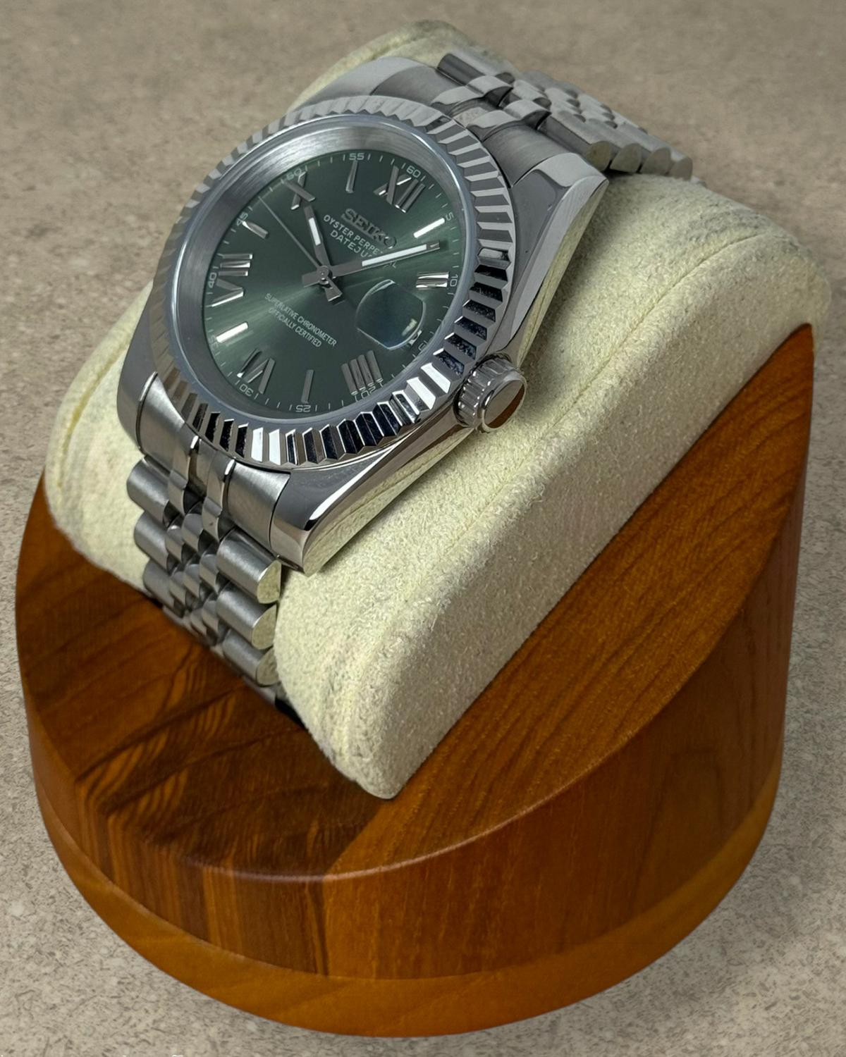 PB TimePiece olive green dial watch with fluted bezel, stainless steel jubilee bracelet, and Roman numeral markers.