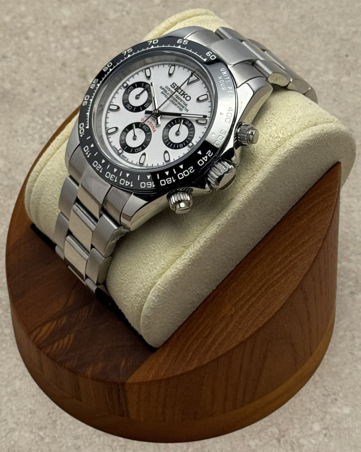 PB TimePiece Panda chronograph watch with white dial, black bezel, and stainless steel oyster bracelet on a stand.