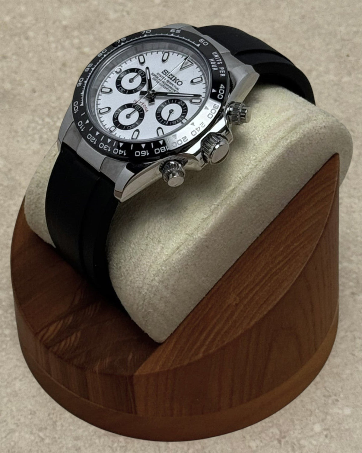 PB TimePiece panda chronograph watch with white dial, black bezel, and black rubber strap on a wooden display stand.