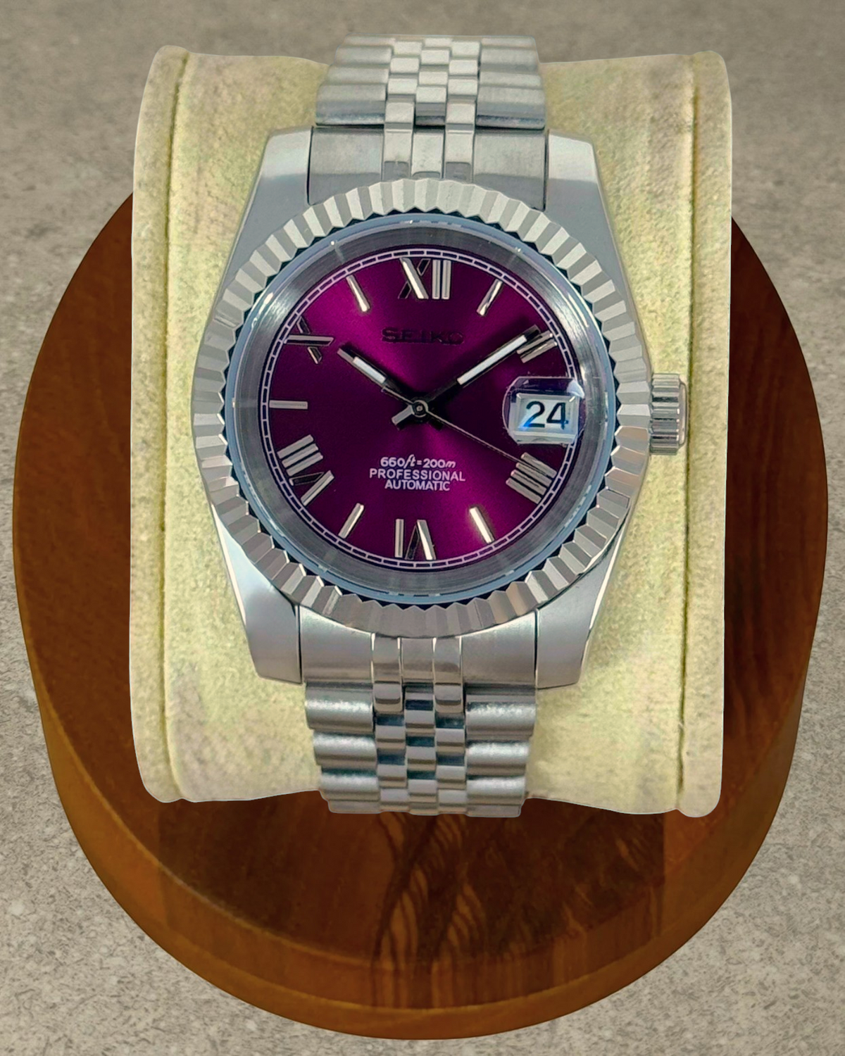 PB TimePiece Classic Date watch with a purple dial, Roman numerals, fluted bezel, and stainless steel jubilee band.