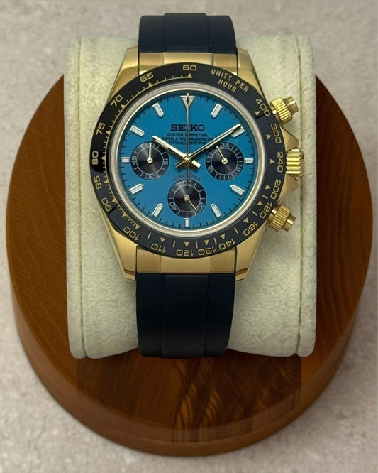 PB TimePiece Riviera chronograph watch with a 39mm gold case, turquoise dial, and black rubber strap.