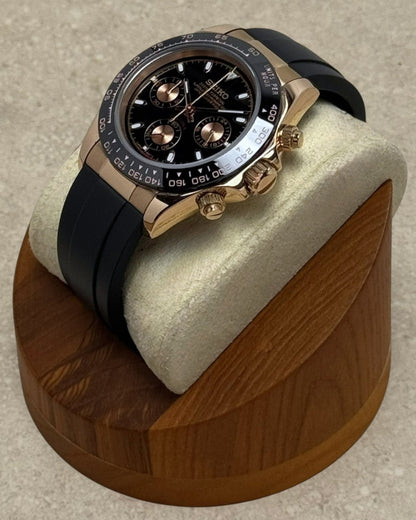 PB TimePiece rose gold chronograph watch with a black dial, black rubber strap, and 39mm case on a wooden stand.