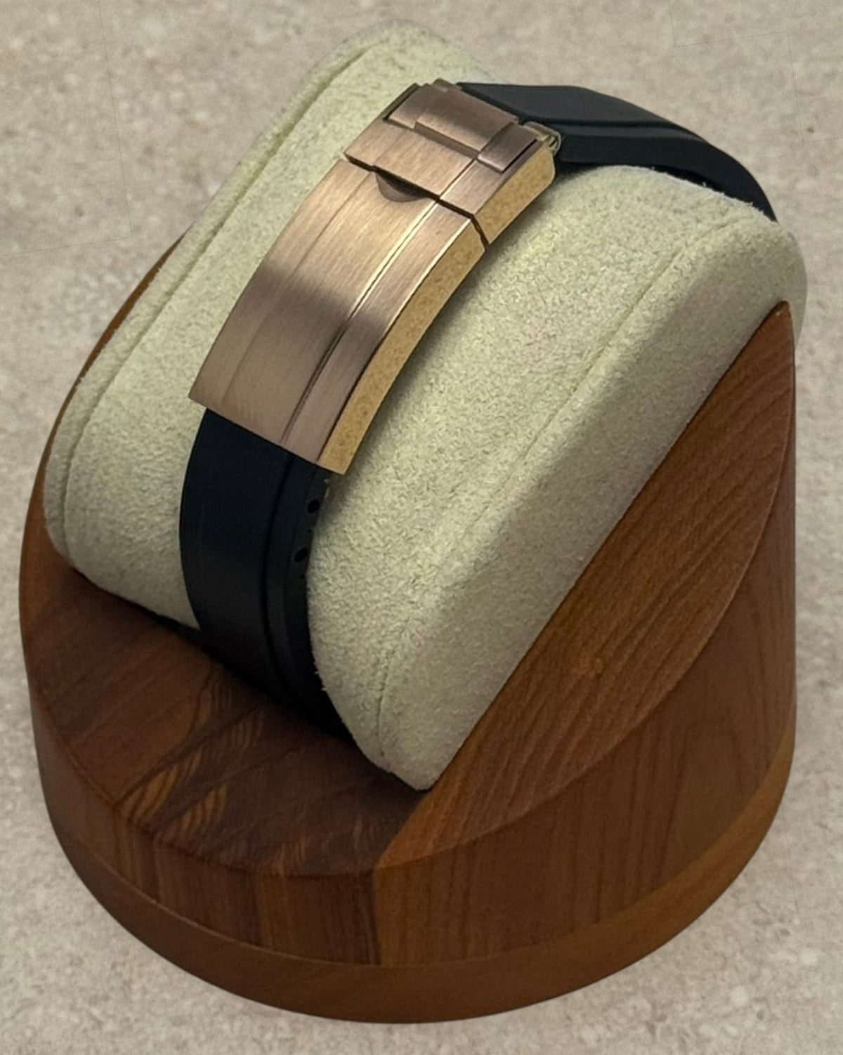 PB TimePiece rose gold microadjusting clasp on a black rubber watch strap displayed on a wooden stand