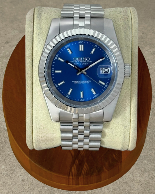 PB TimePiece Classic Date watch with a royal blue dial, fluted bezel, and stainless steel jubilee bracelet.