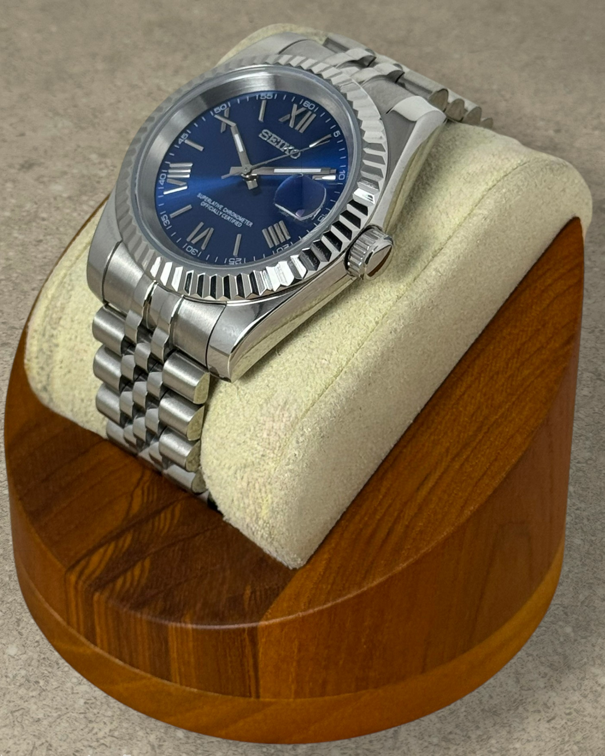 PB TimePiece Classic Date watch with royal blue dial, Roman numerals, fluted bezel, and stainless steel jubilee band.
